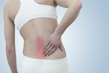 Acute pain in a woman back. Female from behind holding hand to s