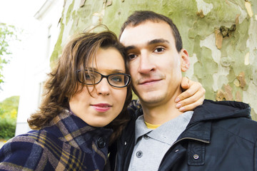 Portrait of love couple embracing outdoor in park looking happy