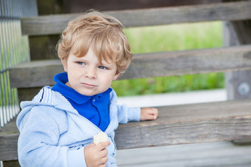 Little toddler boy sitting on wooden stairs