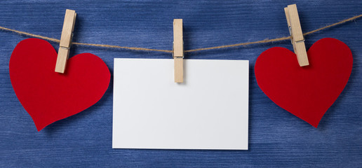 Two paper hearts and card hanging on a rope