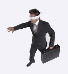 Hombre de negocios vendado,ciego caminando sujetando un maletín. - obrazy, fototapety, plakaty
