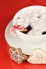 Cup of coffee with Christmas sweetness on red background