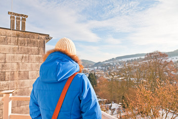 Woman from back looking over village in snow valley.