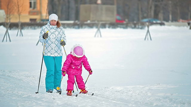 Mother with little child skiing in snowy park