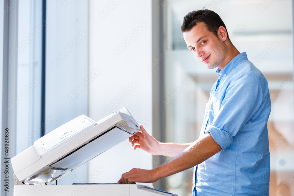 Wall mural Handsome  young man using a copy machine