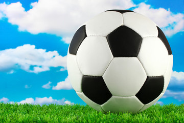 Naklejka premium football ball on green grass, on blue sky background