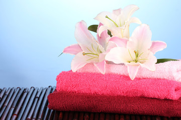 Obraz na płótnie Canvas stos ręczników różowy lilia na niebieskim tle
