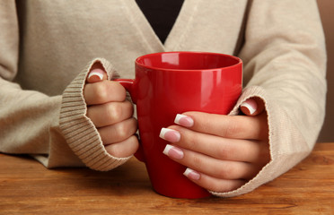 hands holding mug of hot drink, close-up