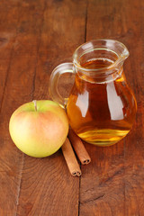 Full jug of apple juice and apple on wooden background