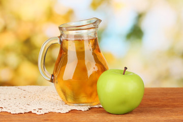 Full jug of apple juice and apple