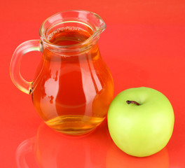 Full jug of apple juice and apple on color background