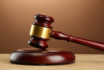wooden gavel on wooden table, on brown background