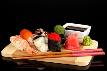 delicious sushi served on wooden board isolated on black