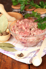 Bowl of raw ground meat with spices on wooden table