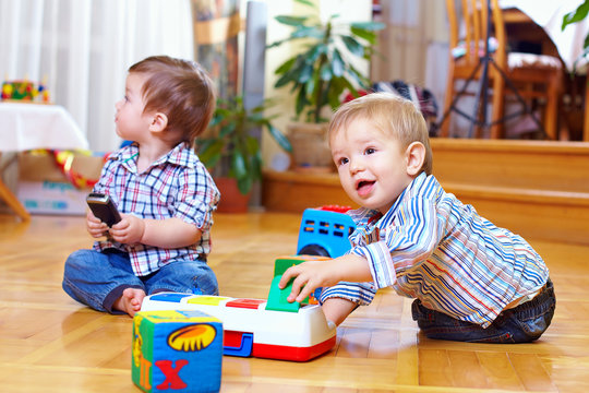 two baby boys playing with toys at home