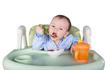 child is eating sitting at table, isolated over white
