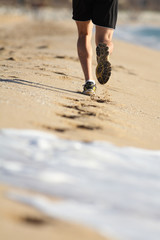 Man legs running on the sand of a beach