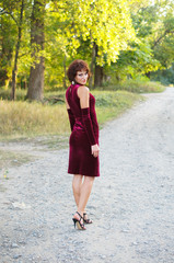 The girl in an evening red dress on the nature