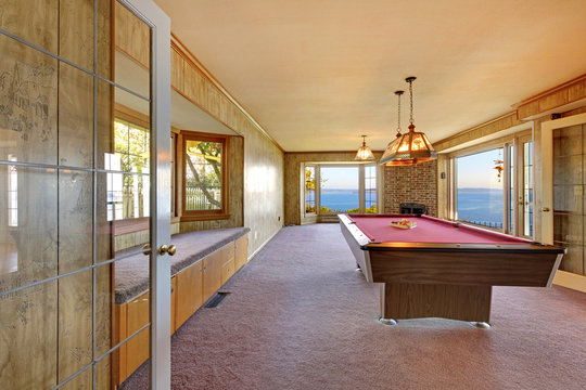 Large old room with pool table, window bench and water view.