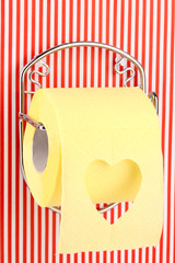 Roll of toilet paper on  holder fixed to pinstriped wall