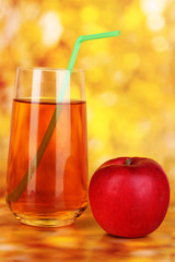 Useful apple juice with apples around on autumn background