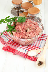 Bowl of raw ground meat with spices on wooden table