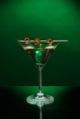 Martini glass and olives on dark background