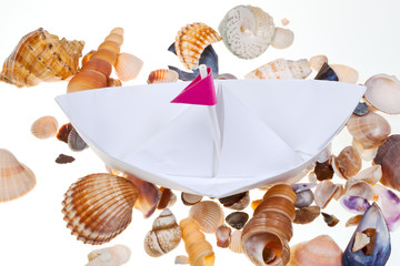 paper boat on background from sea shells