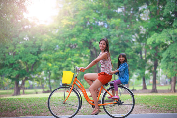 Obraz premium Mother and a daughter cycling bicycle at the park