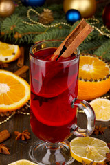 Fragrant mulled wine in glass with spices and oranges around