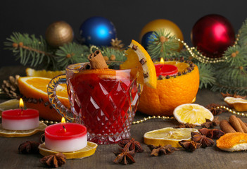 Fragrant mulled wine in glass with spices and oranges around