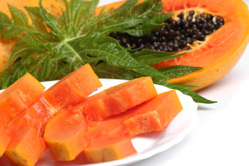 Ripe papaya and slices with seeds and green leaf isolated on a w