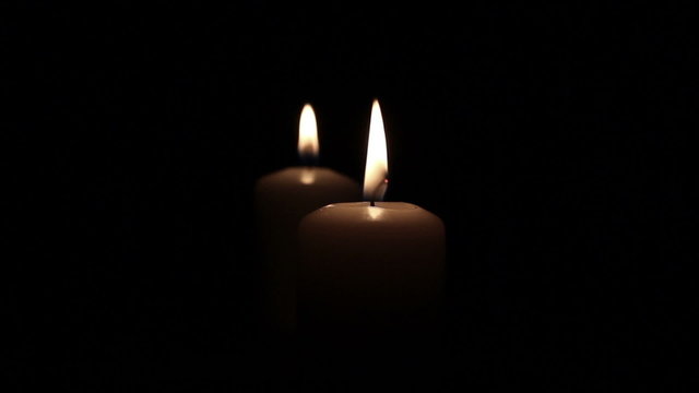 Two romantic  burning candles in dark .