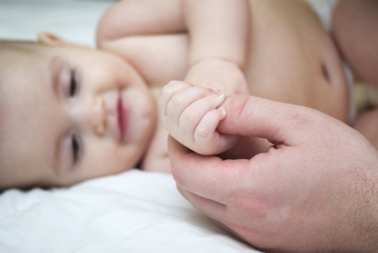 A baby's hand touching an adult's hand