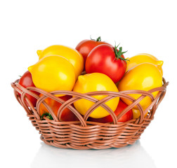 Ripe red and yellow tomatoes in wicker basket isolated on white