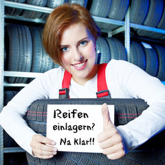 Female apprentice is showing thumb up for tire storing