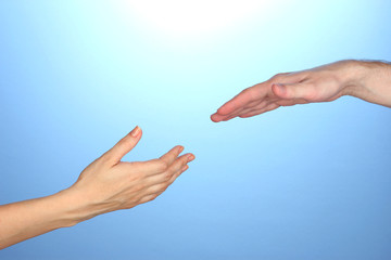 Women's hand goes to the man's hand on blue background
