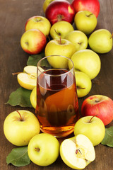 Useful apple juice with apples around on wooden table