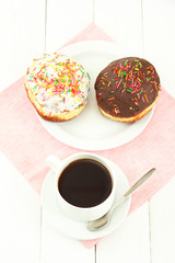 Tasty donuts on color plate on light wooden background