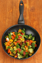Sliced fresh vegetables in pan on wooden table