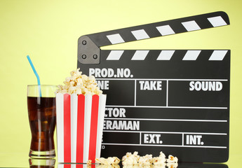 Movie clapperboard, cola and popcorn on background