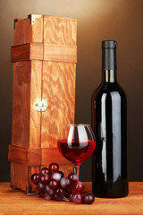 Wooden case with wine bottle on wooden table on brown