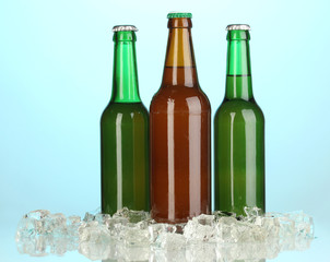 Beer bottles in ice on blue background