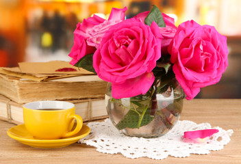Beautiful pink roses in vase on wooden table on room background