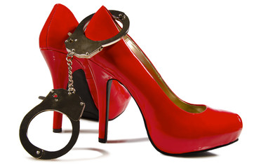 Pair of glossy red high-heeled shoes positioned against a white background. The set of metallic...