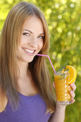 Junge Frau lächelt mit einem Glas Orangensaft