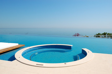 Infinity swimming pool with jacuzzi by beach at the modern luxur