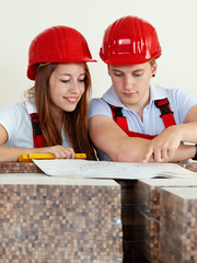 Young worker fixing up a house, discussing in a building lot