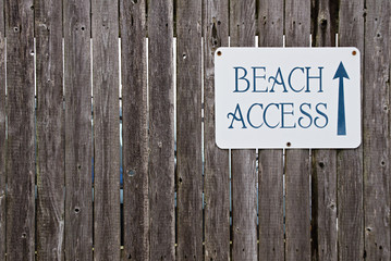 Beach access sign on wooden fence