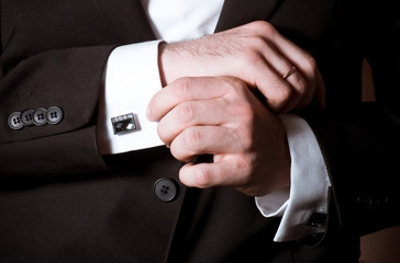 Closeup of a man in black suit correcting a sleeve